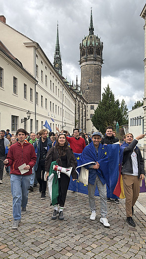 Teilnehmer des Bundeskongresses, z. T. in Europaflaggen eingehüllt oder Europa-Fähnchen schwenkend, demonstrieren auf einer Straße in Wittenberg für Europa.
